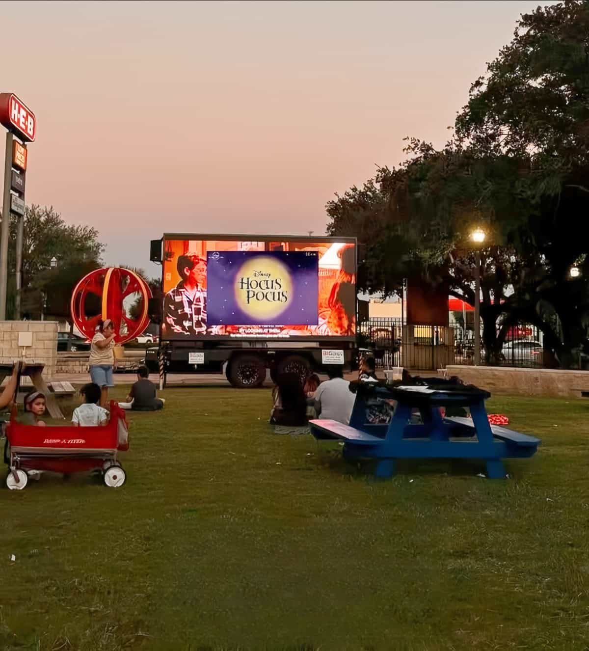 Families at an outdoor community movie night in front of a mobile LED screen